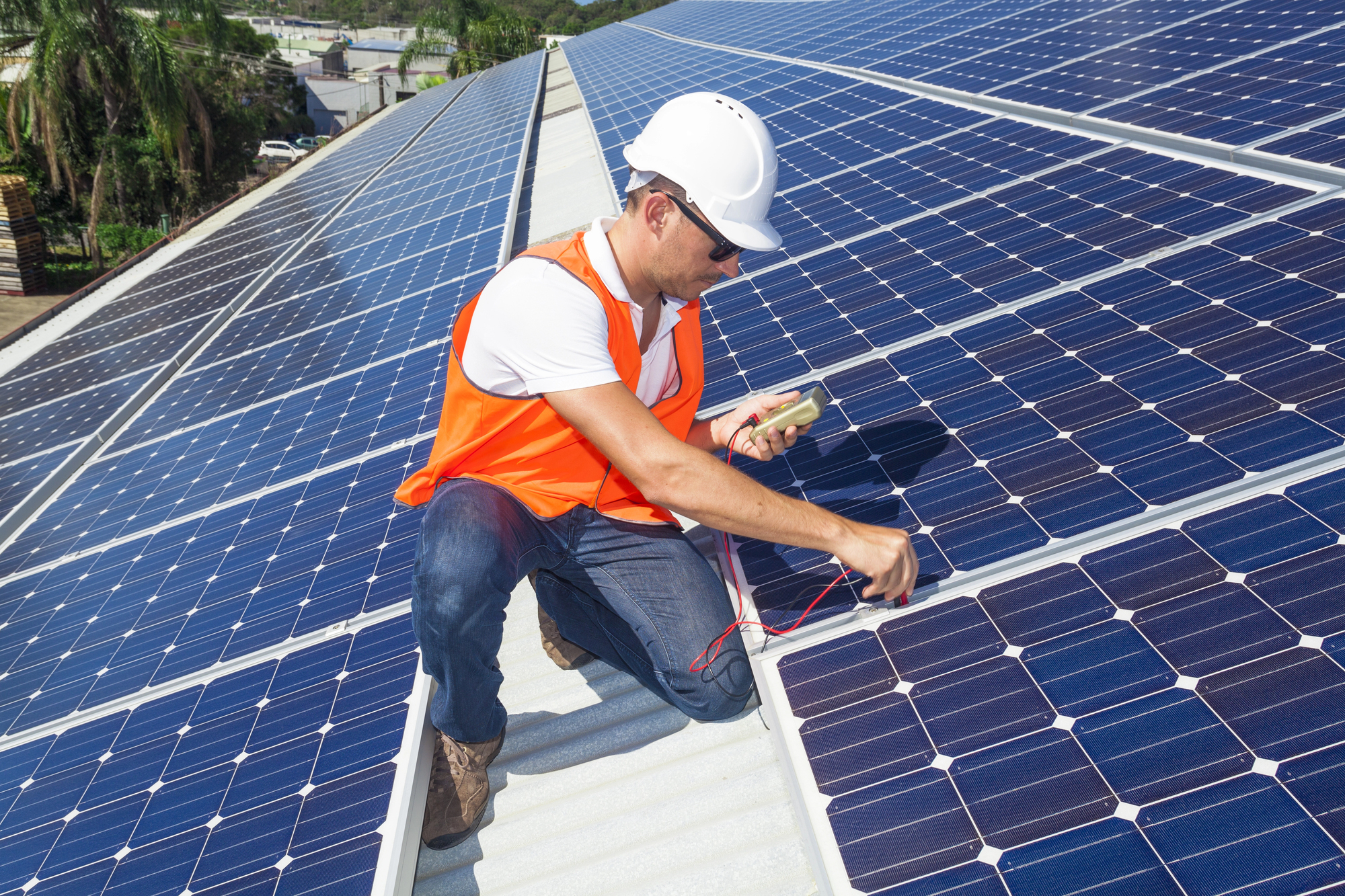 Een technicus inspecteert en meet de prestaties van zonnepanelen op een dak.